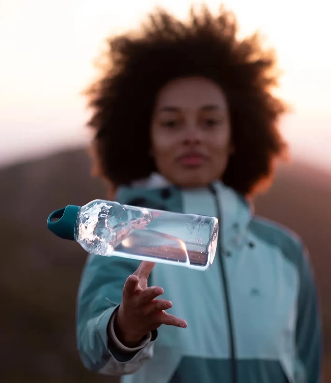 A woman holding a bottle with a liquid inside of it.